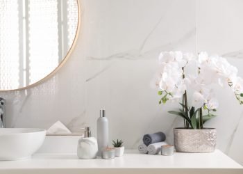 Beautiful flowers, burning candles and different toiletries on c Beautiful flowers, burning candles and different toiletries on countertop in bathroom